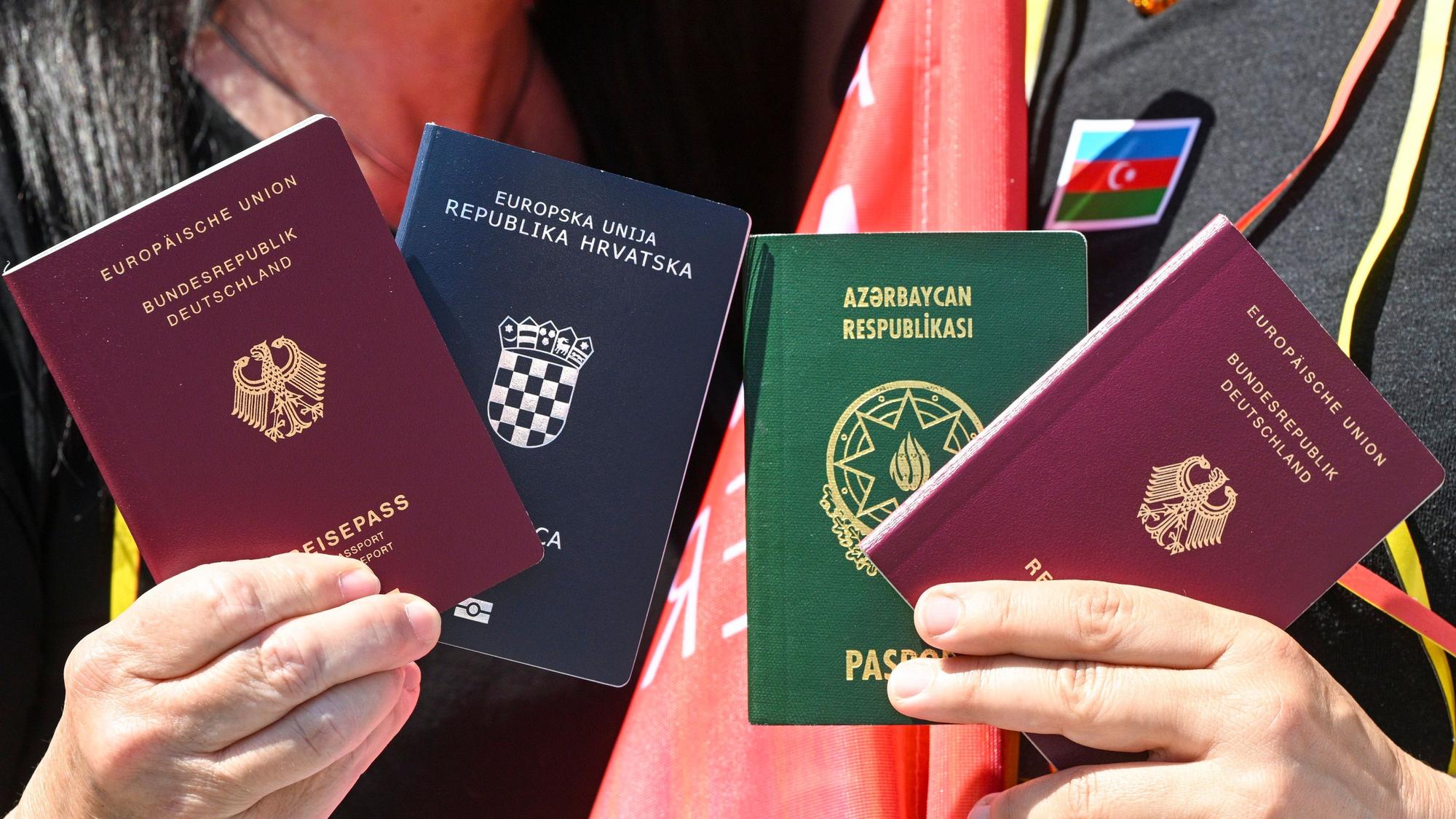 Menschen zeigen bei einem Fototermin zur Unterstützung des neuen Staatsangehörigkeitsrecht die beiden Pässe, den deutschen und den kroatischen und aserbaidschanischen.