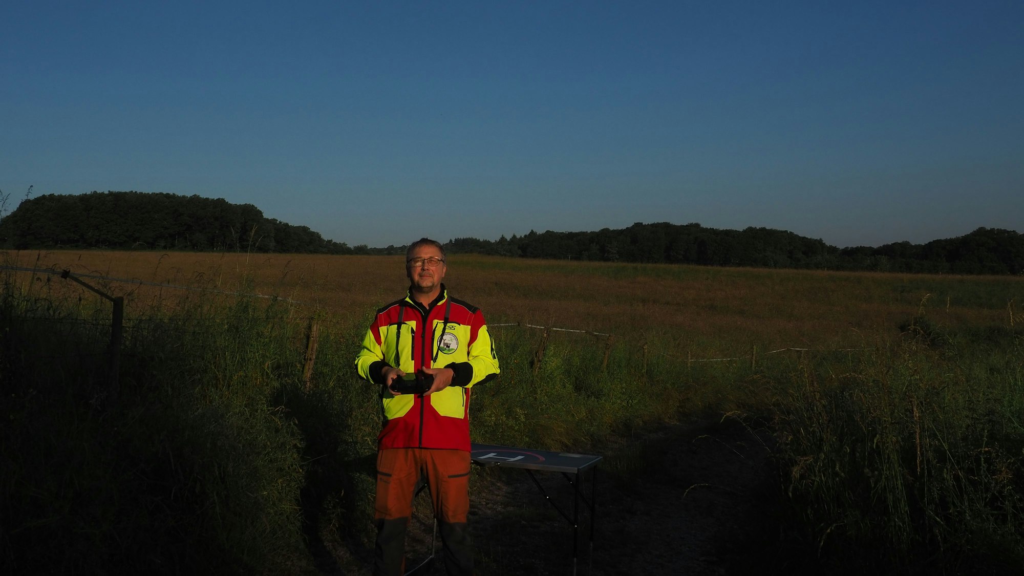 Bernd Osterthun steht auf der Wiese und hält die Steuerung für seine Drohne in der Hand.