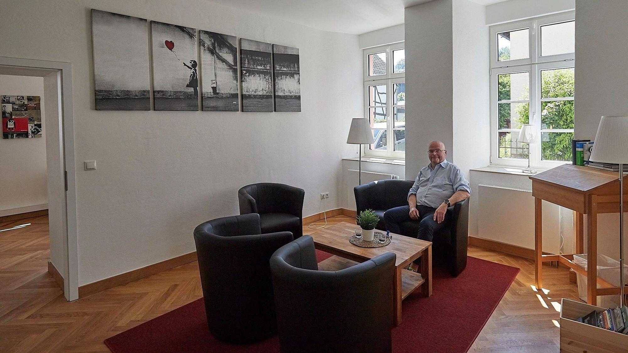 Pfarrer Oliver Joswig sitzt in einem Sessel einer Sitzgruppe in einem neu gestalteten Raum in Alten Pfarrhaus in Hellenthal.