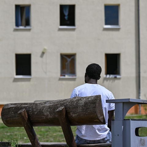 Ein Migrant sitzt auf einer Bank auf dem Gelände der Zentralen Erstaufnahmeeinrichtung für Asylbewerber (ZABH) des Landes Brandenburg.