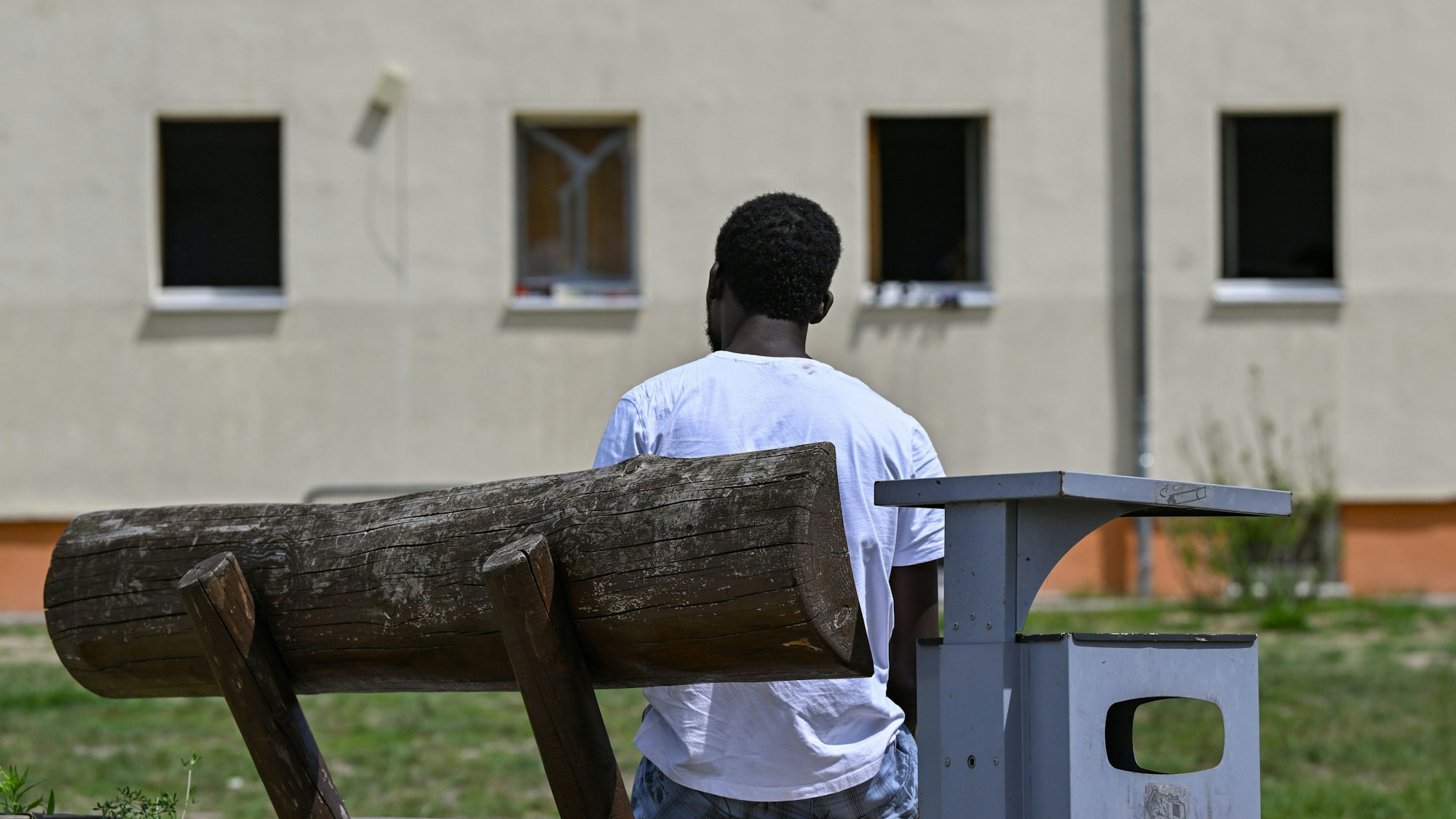 Ein Migrant sitzt auf einer Bank auf dem Gelände der Zentralen Erstaufnahmeeinrichtung für Asylbewerber (ZABH) des Landes Brandenburg.