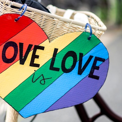 Ein herzförmiges Schild mit der Aufschrift "Love is Love" hängt im Rahmen des CSD (Christopher Street Day) am Fahrrad einer Teilnehmerin.