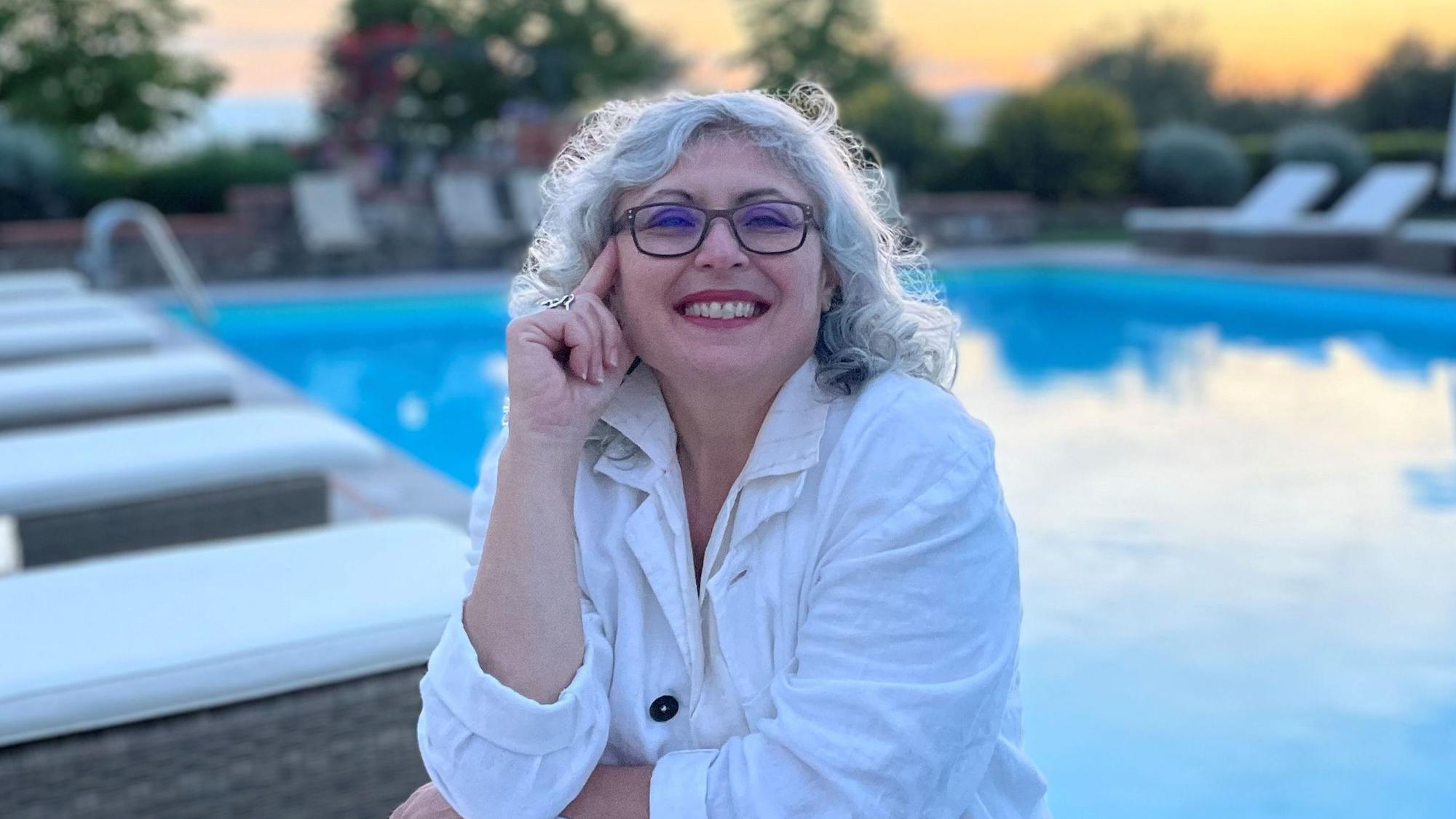 Rita Boyadjian sitzt lächelnd an einem Pool.