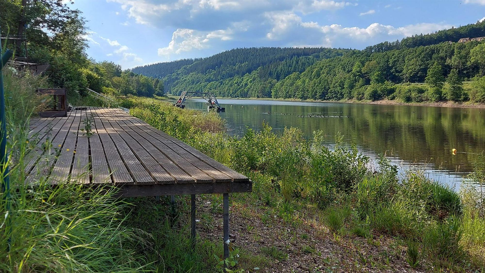 Ein Blick über einen Steg am verwaisten Kronenburger See. Das Wasser steht niedrig.