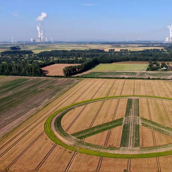 Im Vordergrund ist das Peace-Zeichen zu sehen, im Hintergrund zwei Kraftwerke.