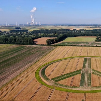 Im Vordergrund ist das Peace-Zeichen zu sehen, im Hintergrund zwei Kraftwerke.