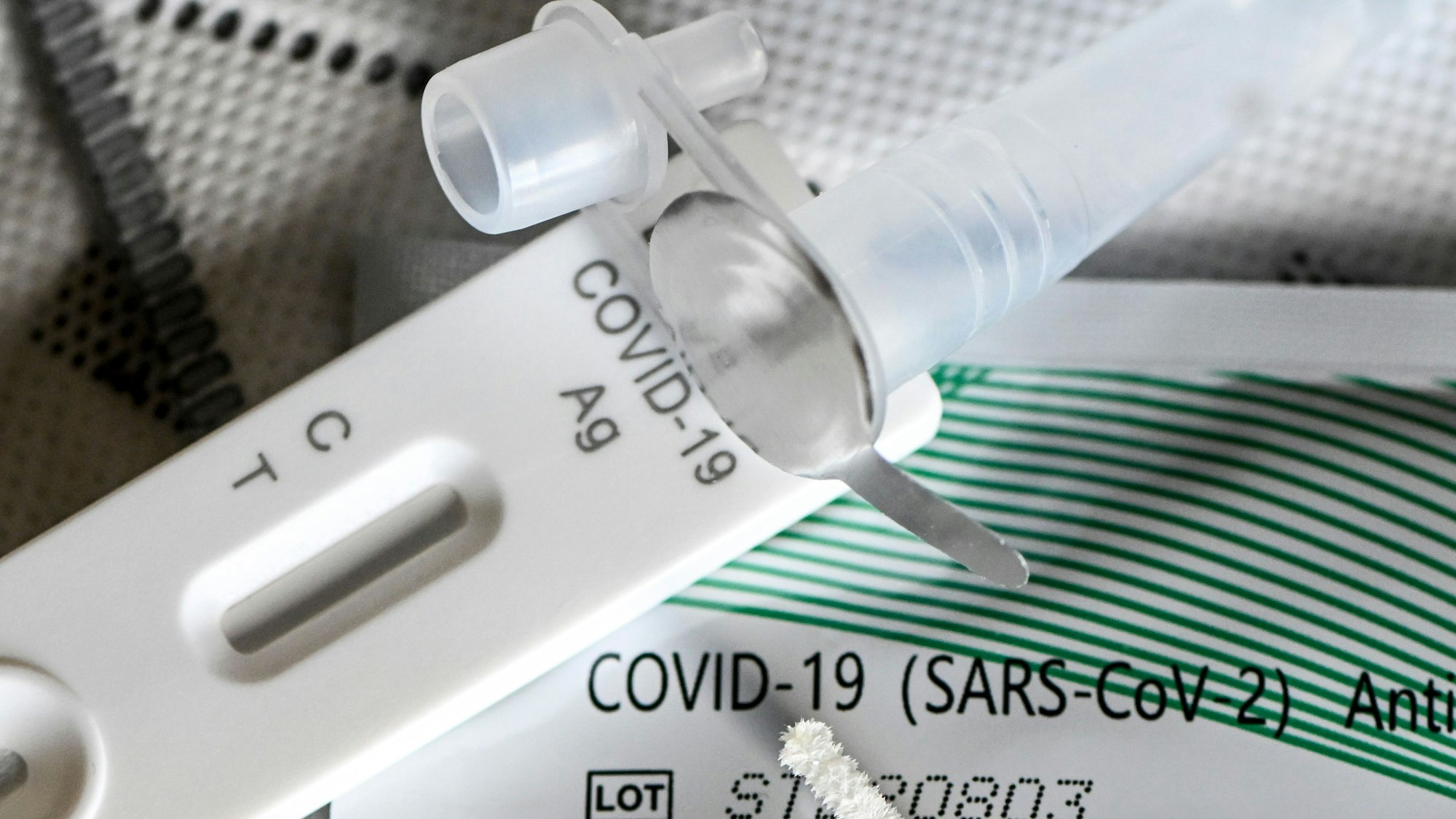 Ein Selbsttest für Covid-19 liegt auf mehreren FFP2-Masken.