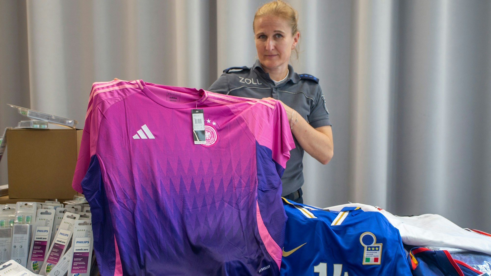 Eine Zollbeamtin zeigt im Rahmen der Jahrespressekonferenz des Hauptzollamts Köln gefälschte EM-Trikots.