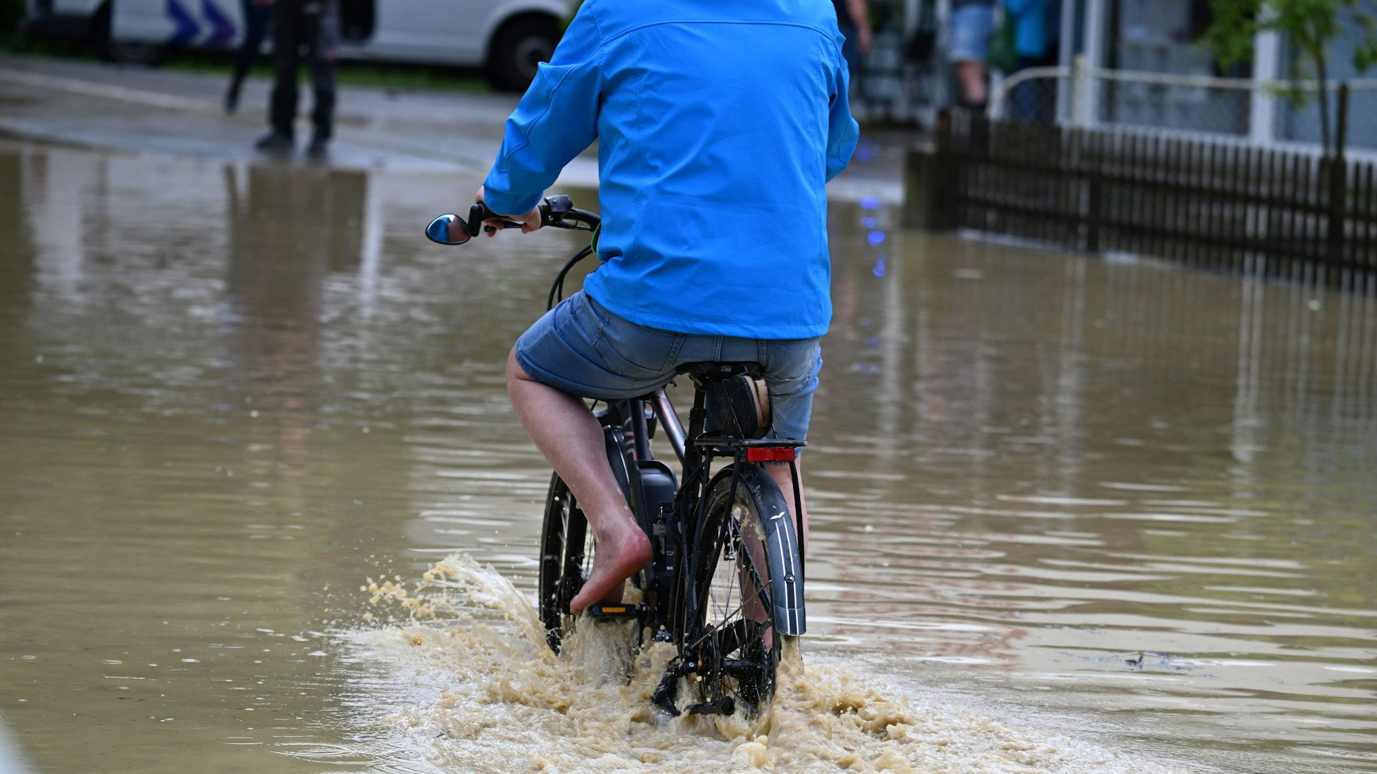 Ein Radfahrer ist auf einer überfluteten Straße unterwegs. Im Bodenseekreis und im Landkreis Ravensburg sind nach Polizeiangaben örtlich einige Keller vollgelaufen.