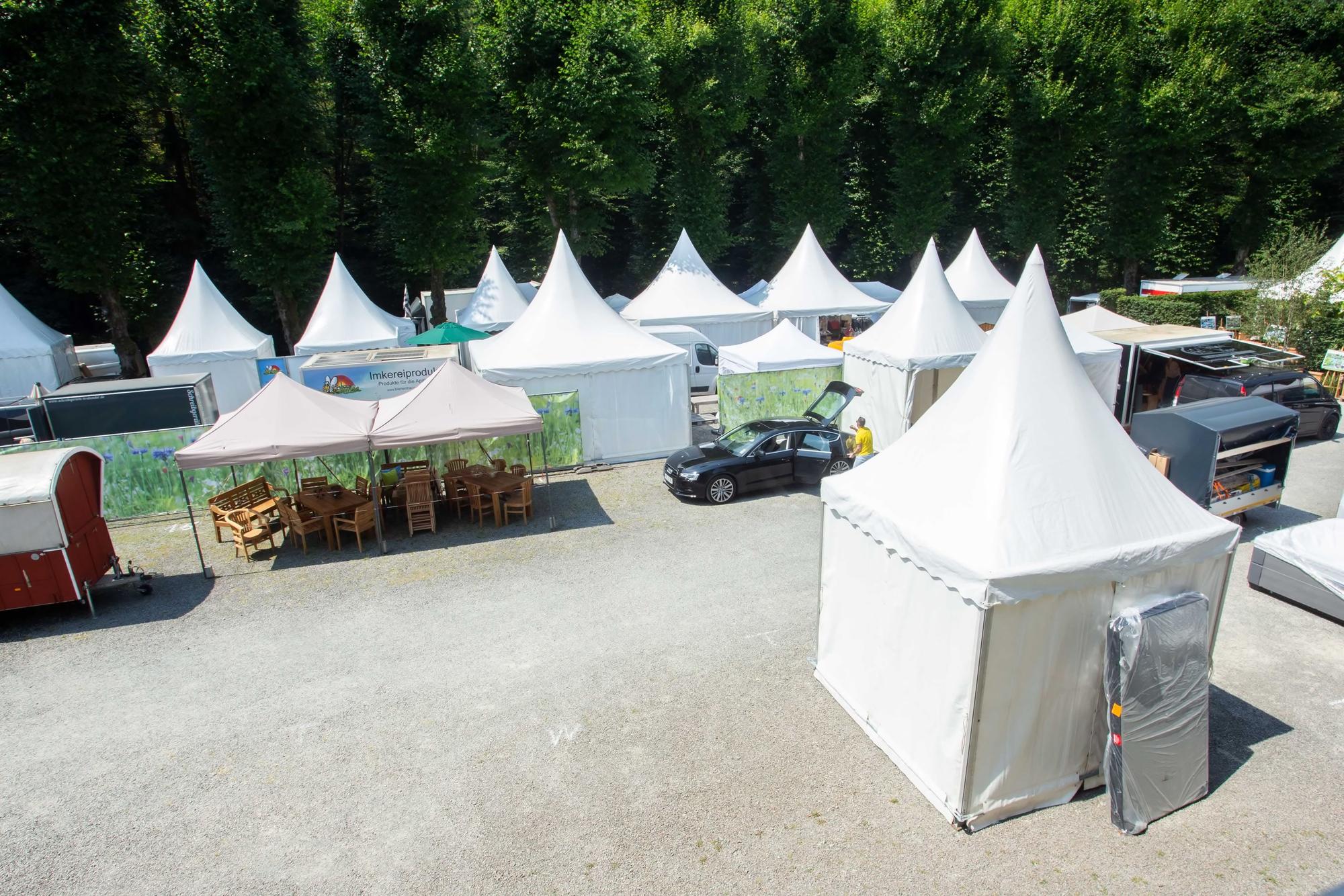 Weiße Pavillons stehen teils noch im Aufbau auf einem Platz.
