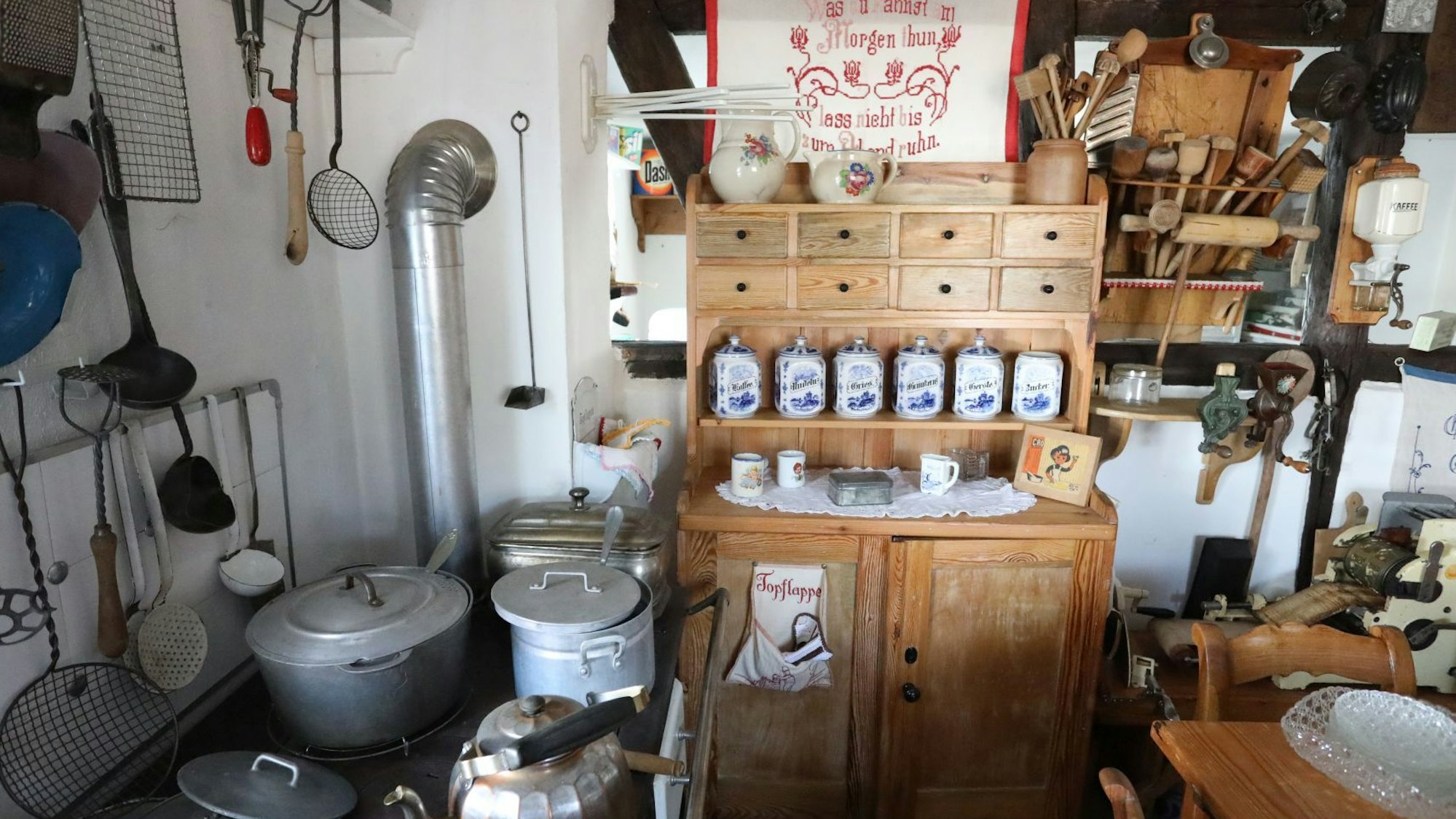 Eine Küche mit altem Holzofen, Töpfen und Schränken.