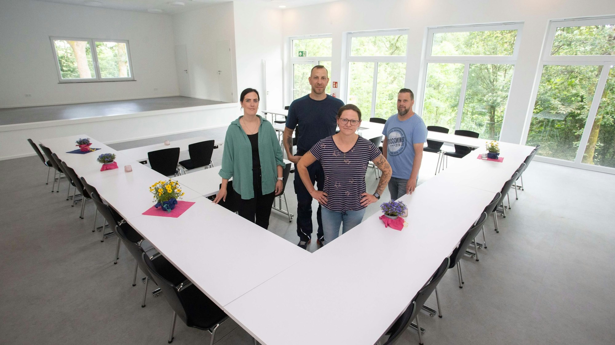 Vier Personen in der Mitte eines hellen Saals.