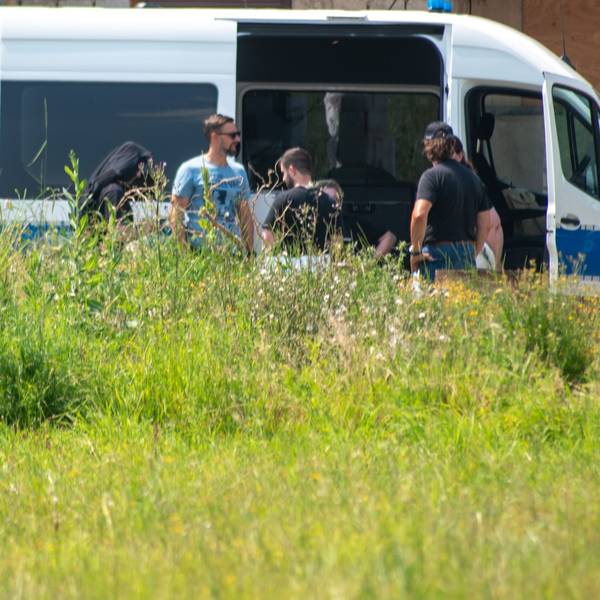 Mitarbeiter des LKA sind in Füssenich im Einsatz. Sie stehen vor einem blau-weißen Polizei-Auto.