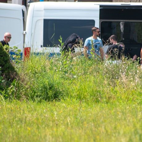 Mitarbeiter des LKA sind in Füssenich im Einsatz. Sie stehen vor einem blau-weißen Polizei-Auto.