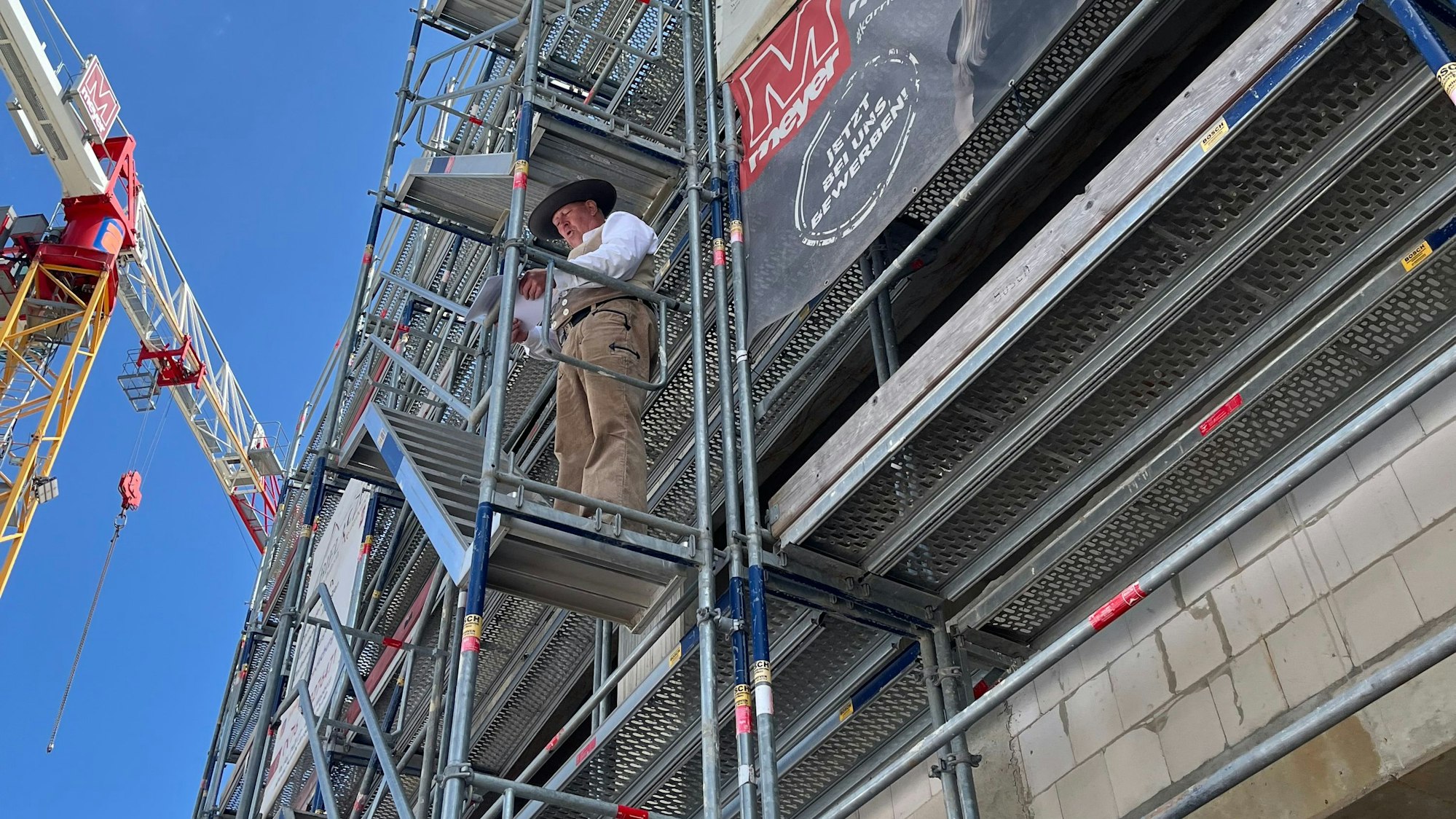 Der Polier steht auf dem Gerüst.