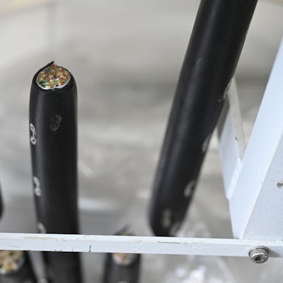 Dicke, schwarze Kabel mit weißen Telefonsymbolen sind durchgeschnitten. In einem sieht man die zahlreichen Kupferadern.