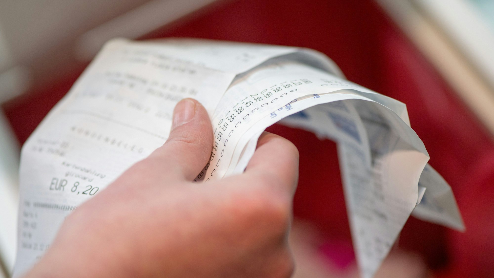 Eine Hand hält mehrere Kassenzettel.