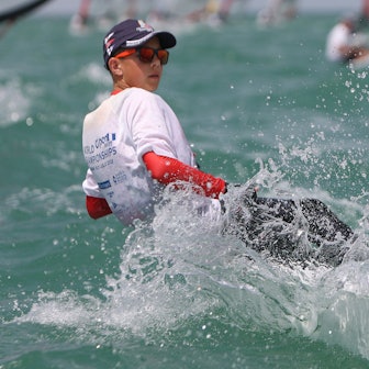 Florian Tempel hängt über dem Wasser und steuert sein Segelboot durch die Wellen.