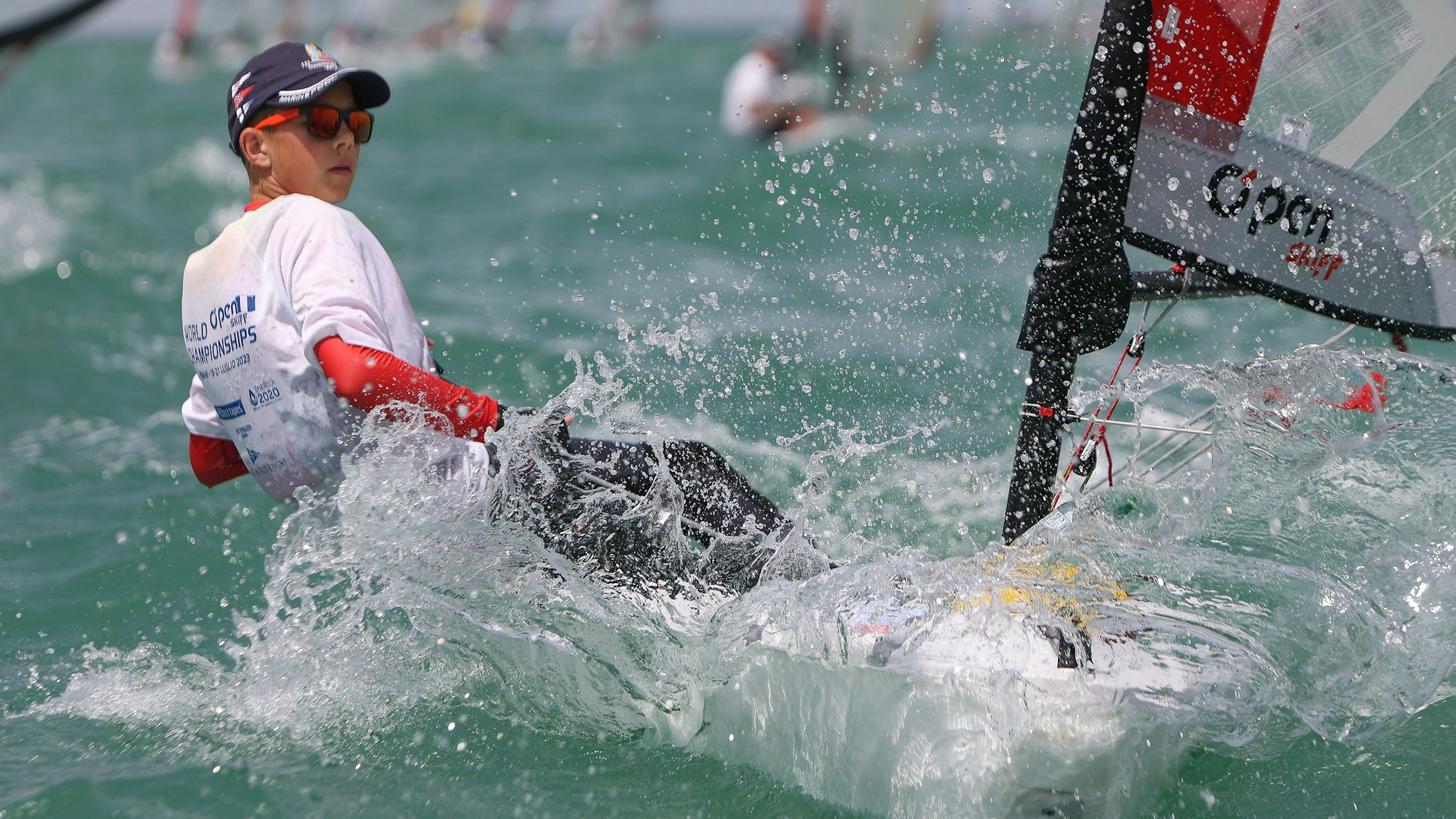 Florian Tempel hängt über dem Wasser und steuert sein Segelboot durch die Wellen.