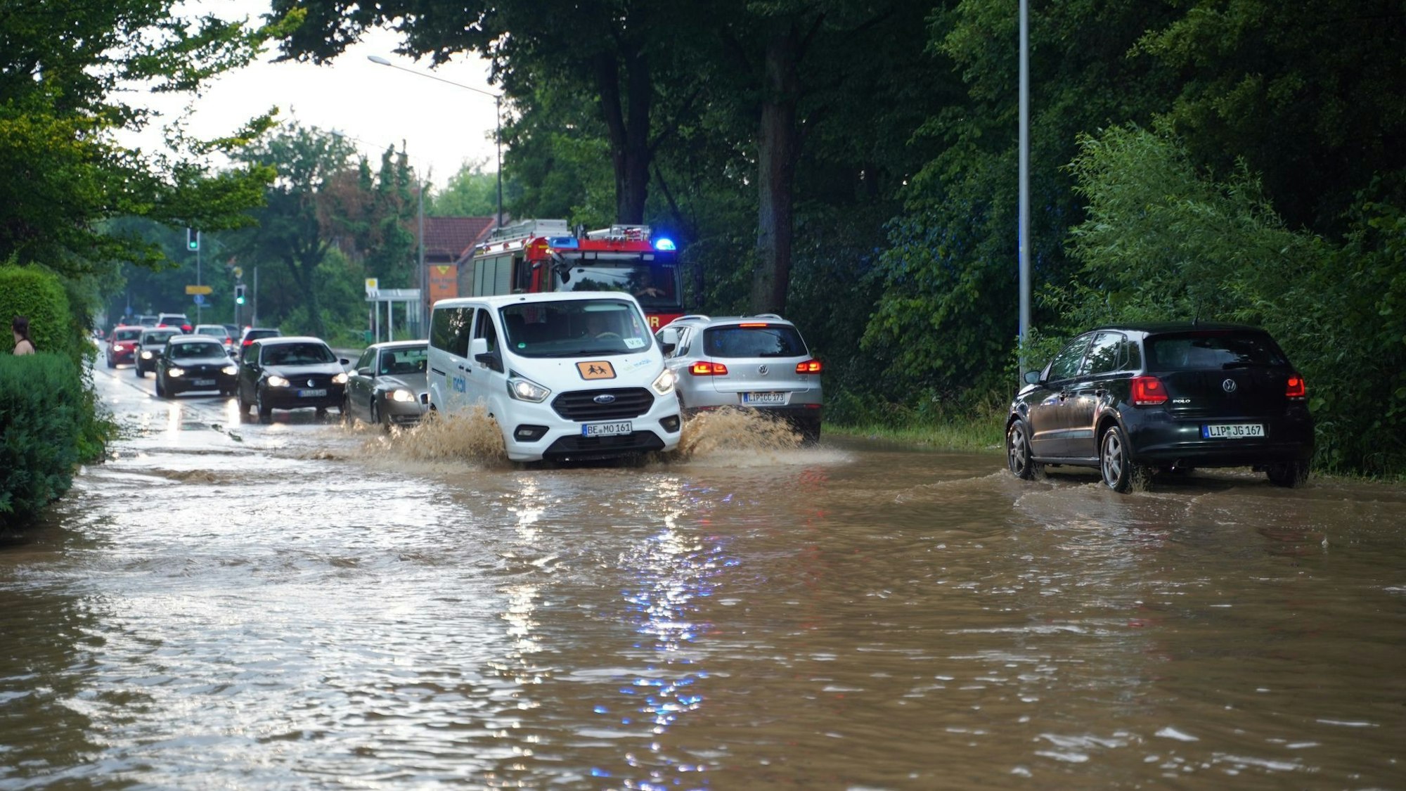 Autos fahren nach einem Unwetter durch Wasser, das auf einer überfluteten Straße steht. Bei einem heftigem Unwetter in Detmold im Kreis Lippe sind nach Stadtangaben binnen kurzem bis zu 100 Liter Regen pro Quadratmeter gefallen.