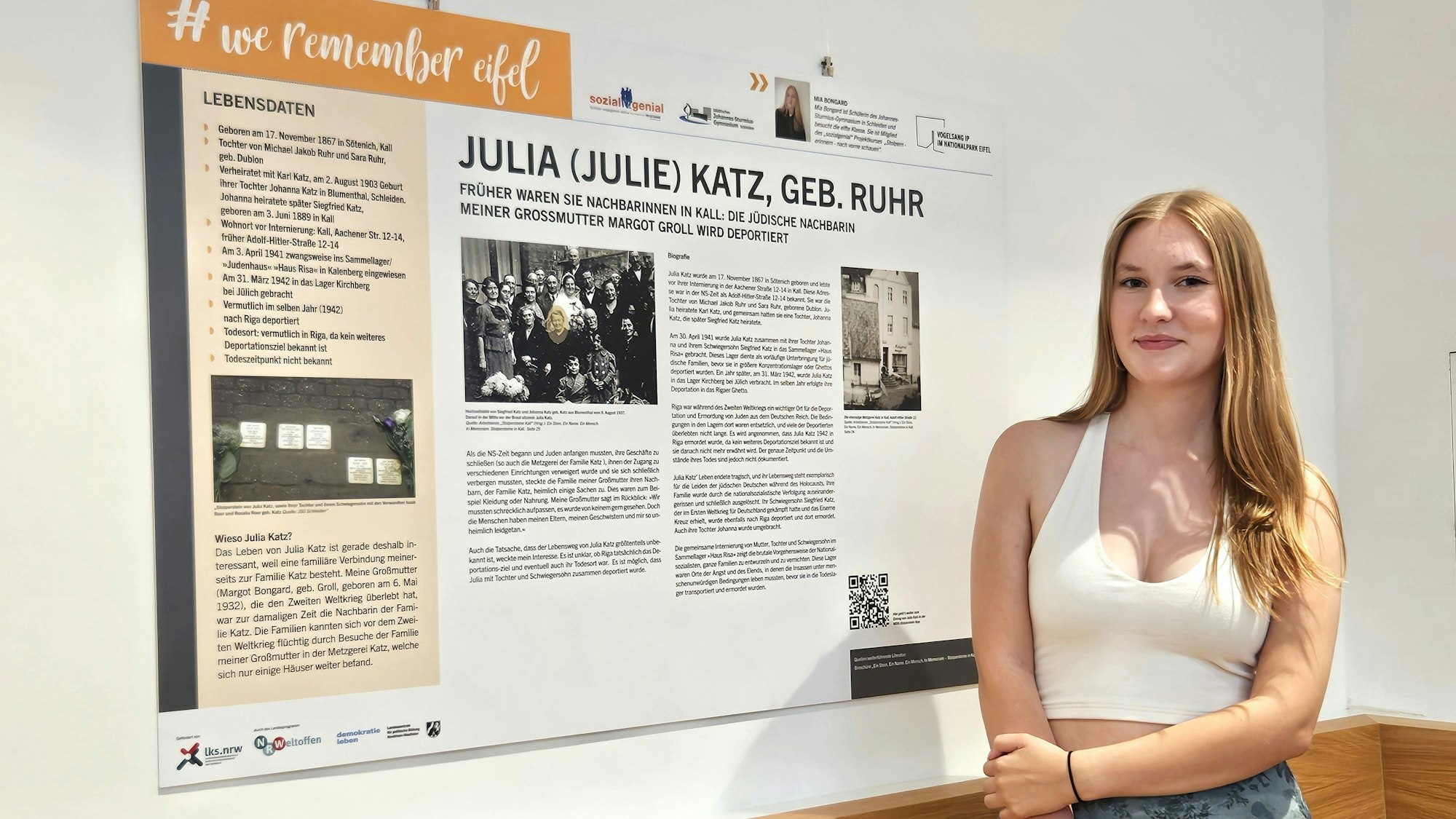 Mia Bongard steht neben der Informationstafel über Julia Katz.
