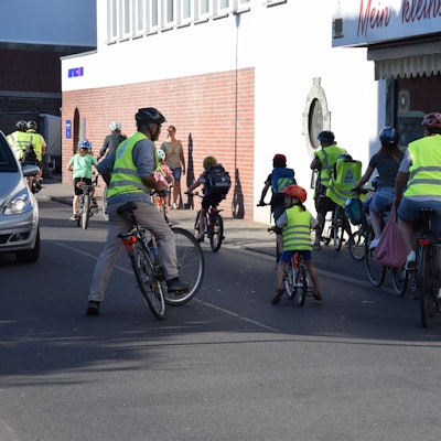 Erwachsene und Kinder sind in Warnwesten auf ihrem Fahrrad unterwegs.