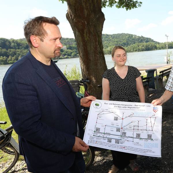 Zwei Männer und eine Frau zeigen einen Plan.