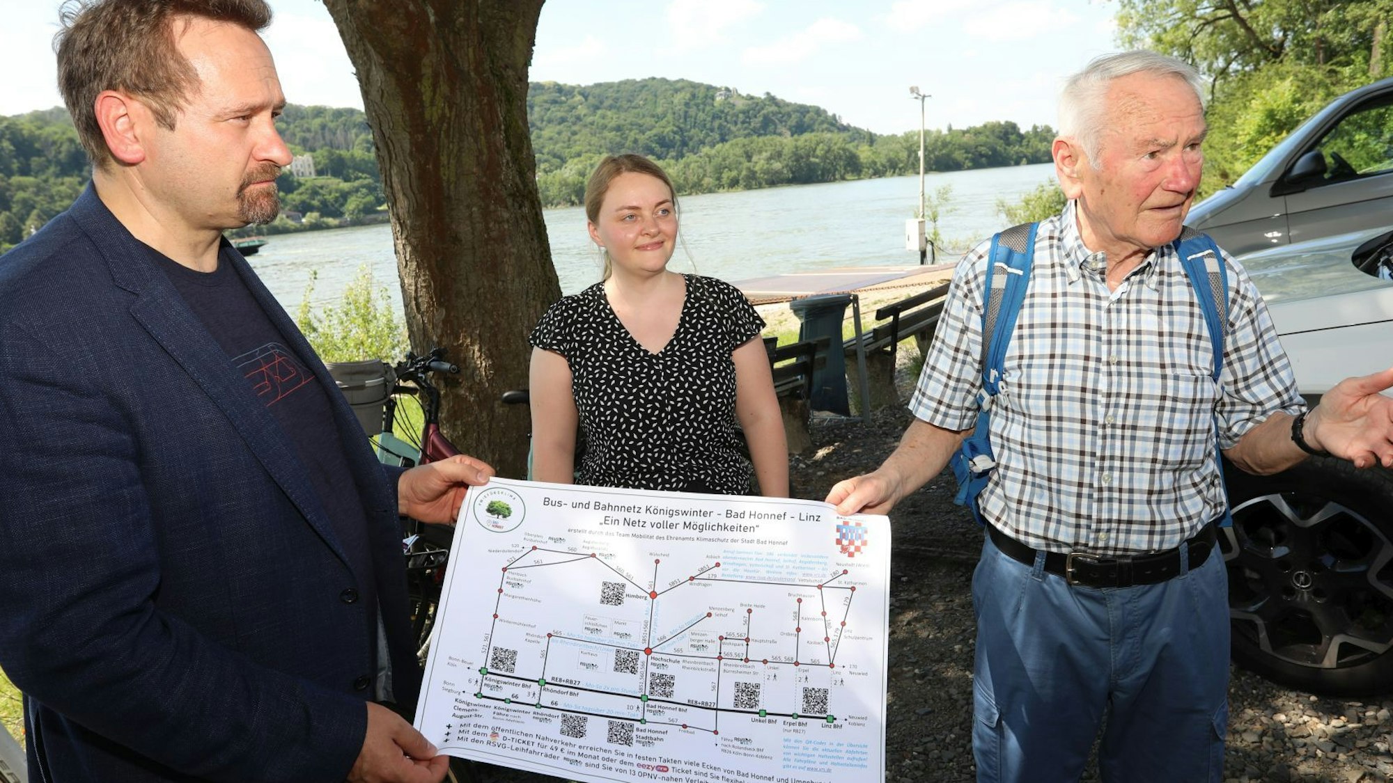 Zwei Männer und eine Frau zeigen einen Plan.