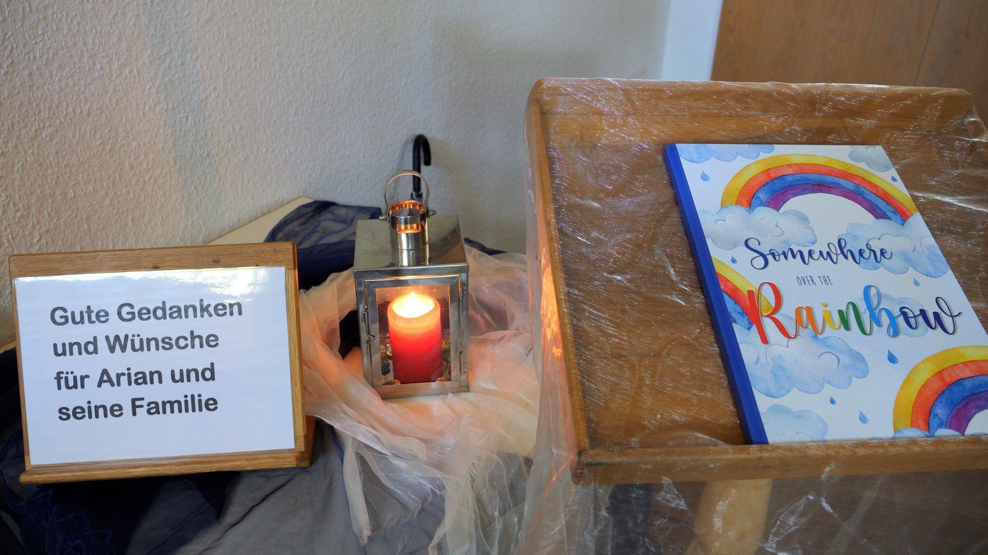 Ein Schild steht neben einer Kerze und ein Buch mit einem Regenbogen auf dem Umschlag liegt daneben in der Kirche der Gemeinde Elm - ein Ortsteil von Bremervörde.