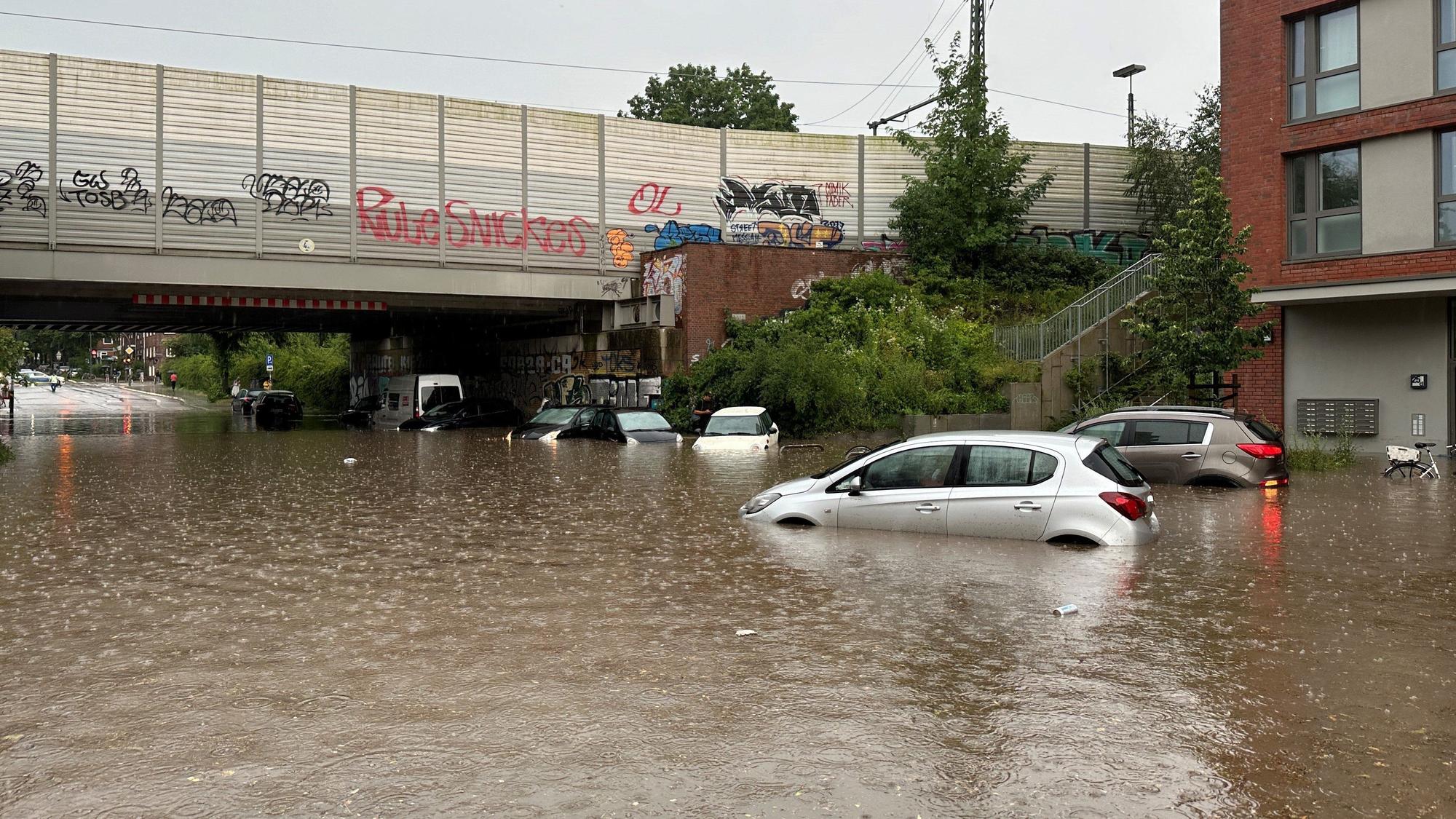 Mehrere Autos stehen bei Regen in einer überfluteten Straße der Unterführung Alte Wöhr in Barmbek-Nord.