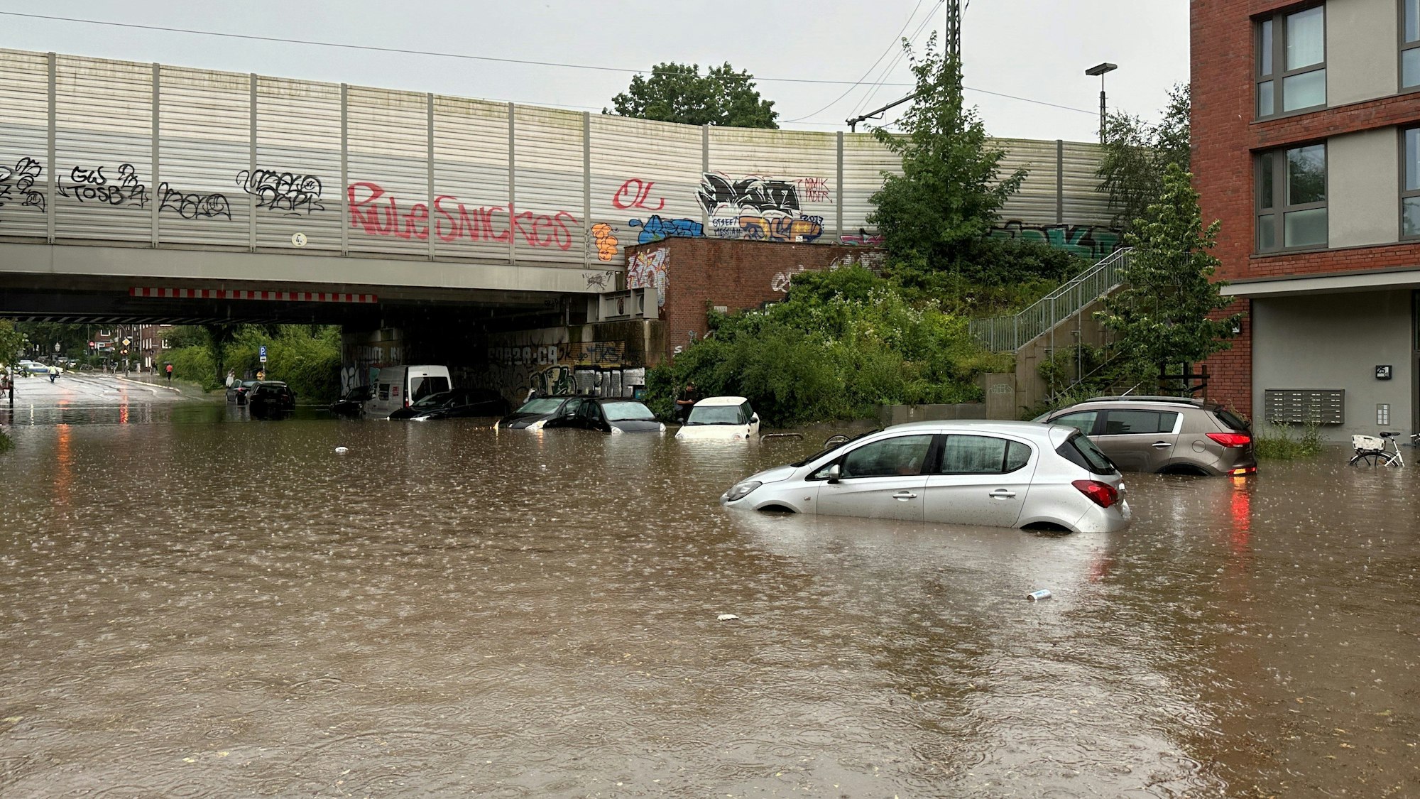 Mehrere Autos stehen bei Regen in einer überfluteten Straße der Unterführung Alte Wöhr in Barmbek-Nord.