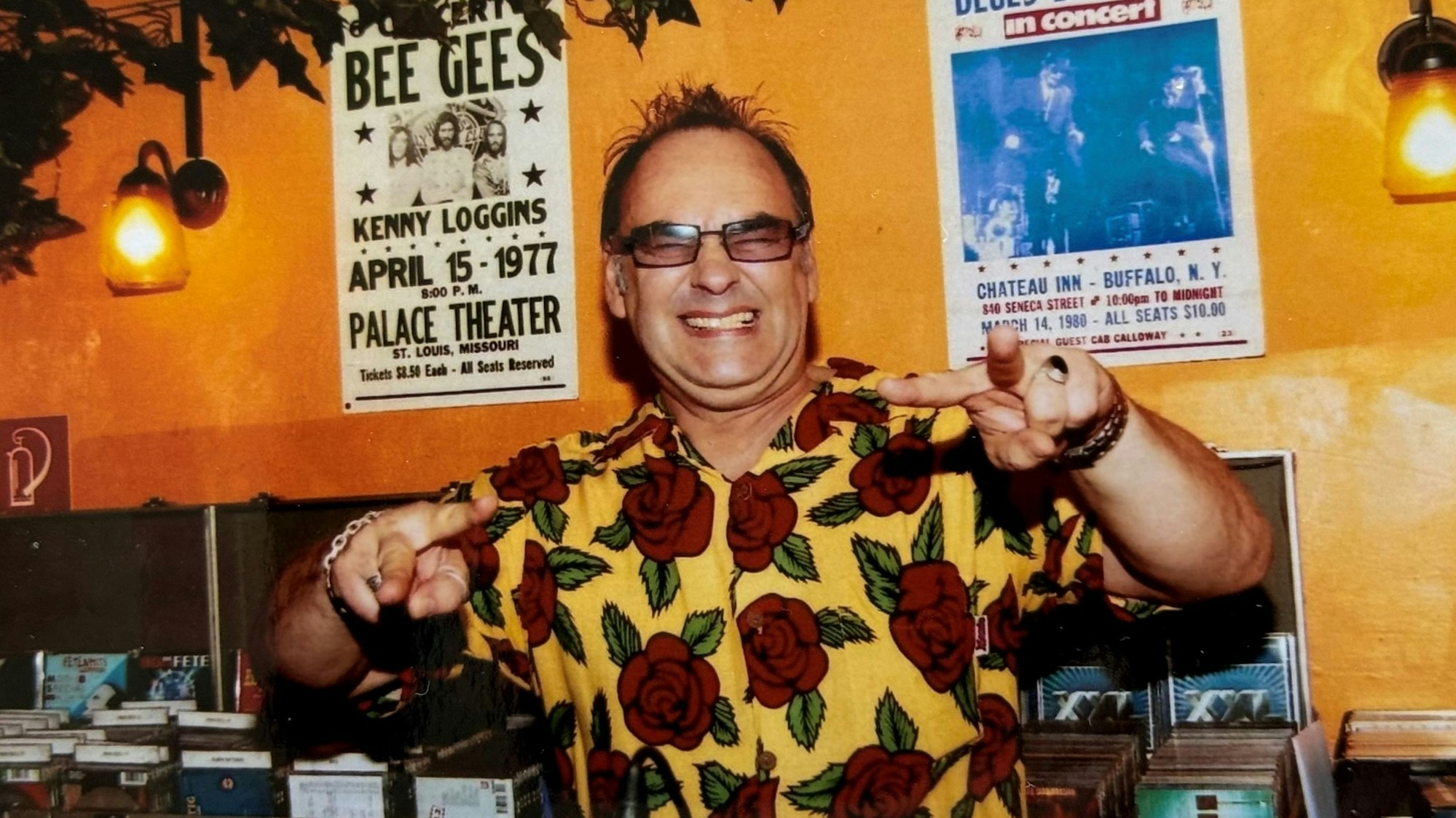 Ein Mann in buntem Hawaii-Hemd steht hinter einem DJ-Pult.