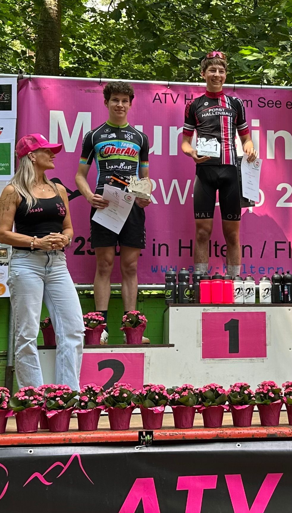 Siegerfoto in der U17-Altersklasse. Neben den beiden Erstplatzierten steht eine Frau mit rosa Kappe.
