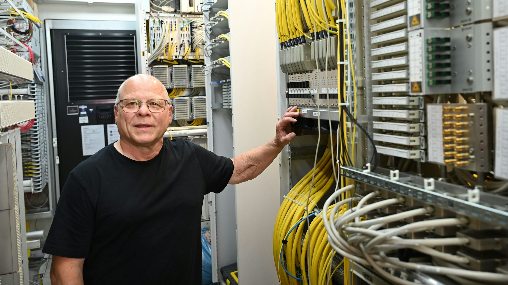 Gerd Wolter steht in einem Container an gelben Kabeln, die in zahlreichen Schaltschänken der Telekom verlaufen.