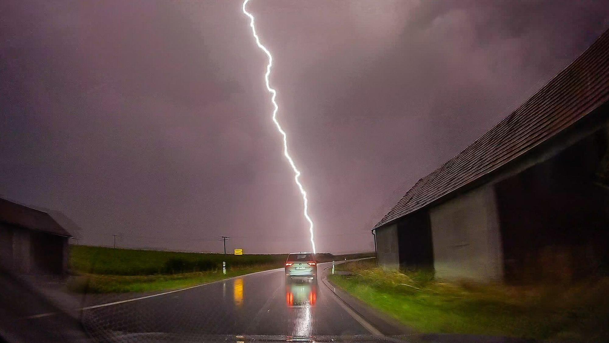 Bayern, Pförring: Ein Blitz ist am Himmel hinter einer Straße zu sehen.