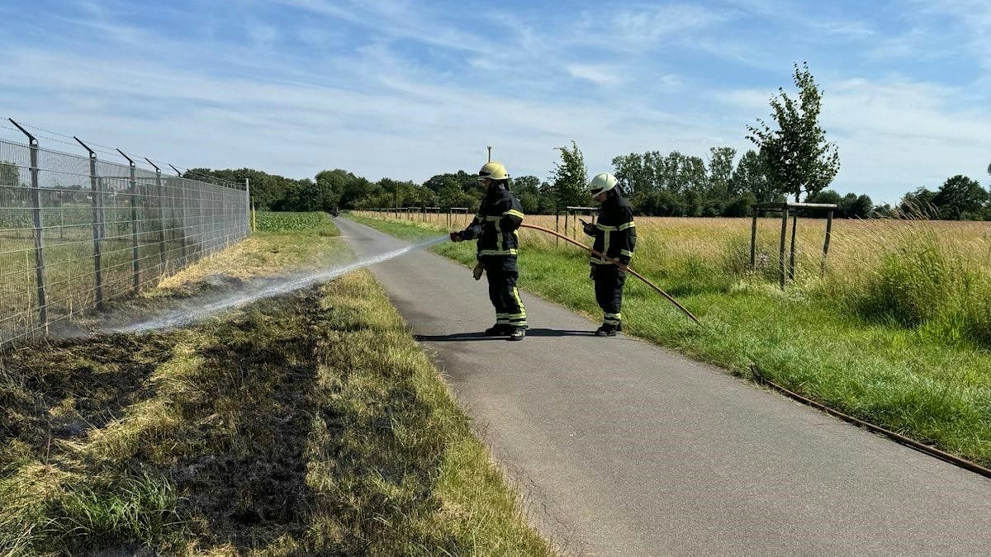 Feuerwehrleute löschen den Flächenbrand in Erftstadt-Köttingen.