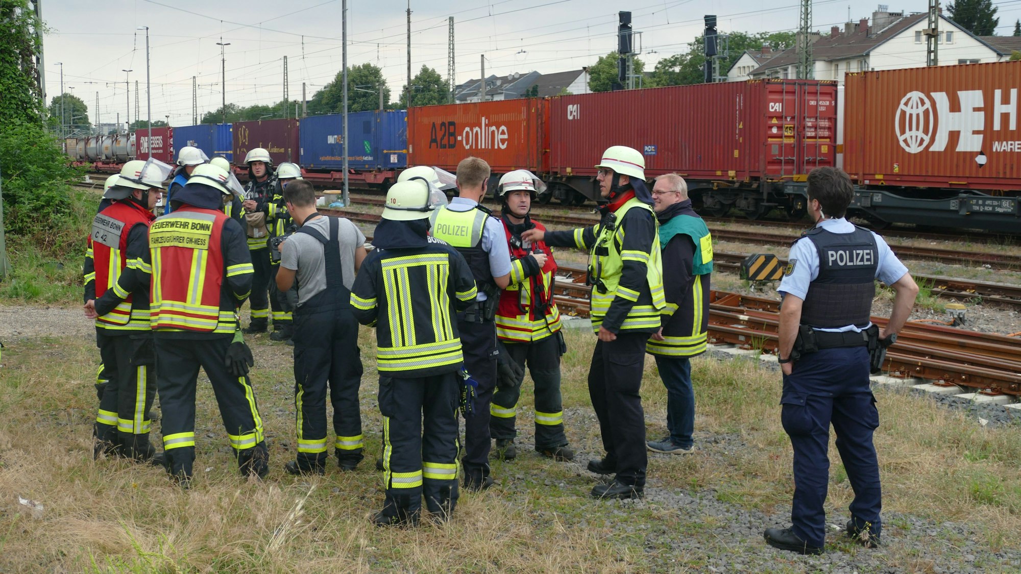 Feuerwehrleute stehen neben Bahngleisen.