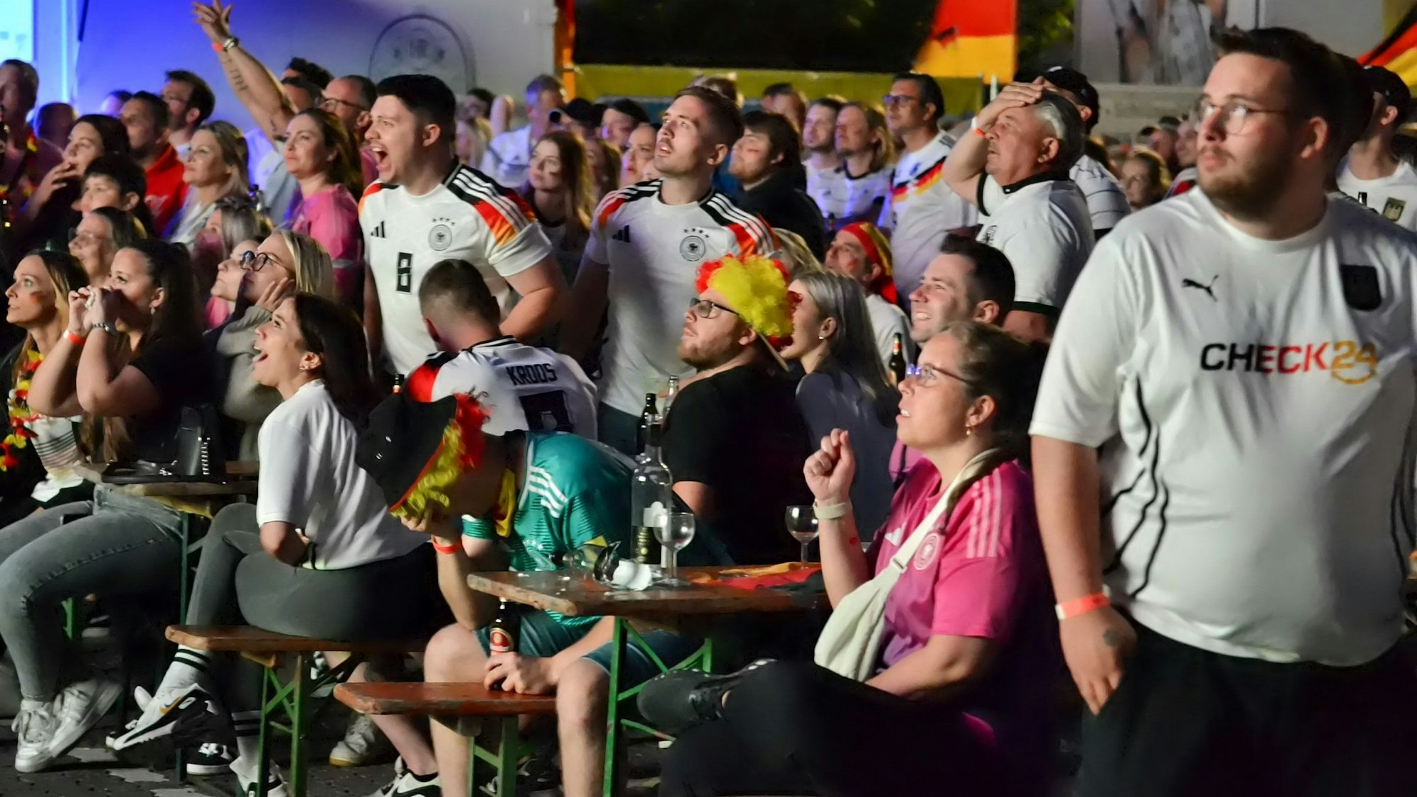 Fans sitzen und stehen beim Public Viewing des EM-Spiels Deutschland gegen Dänemark dicht beieinander.