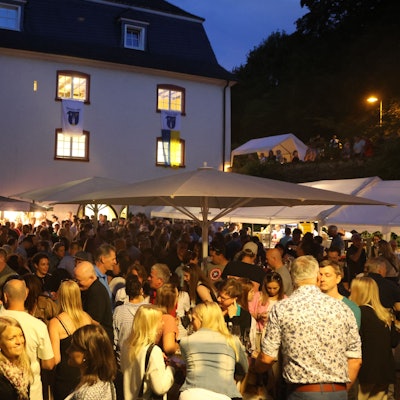 Eine große Menschenmenge in der Dämmerung vor dem Burghaus.
