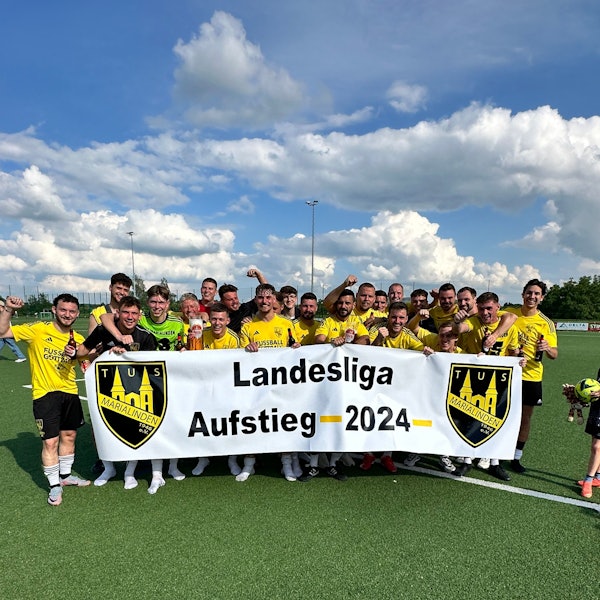 Das Team feiert mit einem Banner den Aufstieg