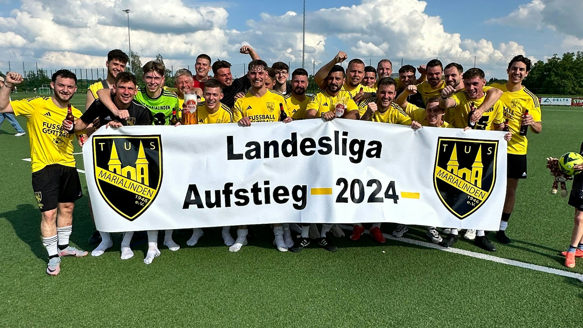 Die Elf des TuS hält ein Aufstiegsbanner hoch