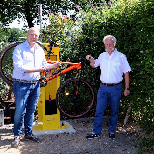 Auf dem Bild ist die neue Radstation mit zwei Männern zu sehen.