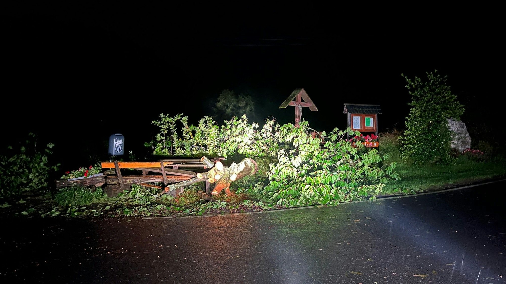 In Hennef-Kraheck stürzte ein Baum um. Feuerwehrleute beseitigten ihn, kurz vor einem Großeinsatz in der Ortschaft dahinter.