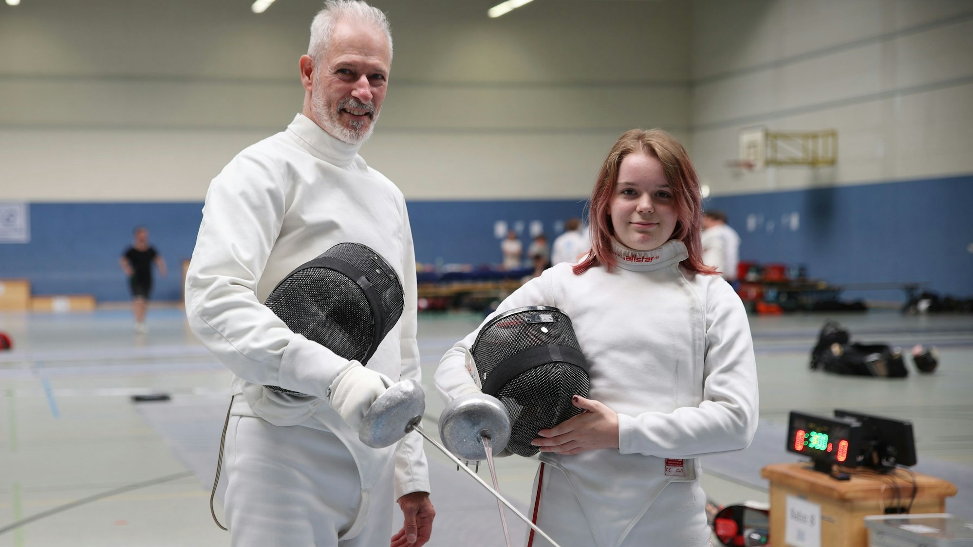 Zu sehen sind eine Degen-Fechterin und ein Degen-Fechter mit Ausrüstung.