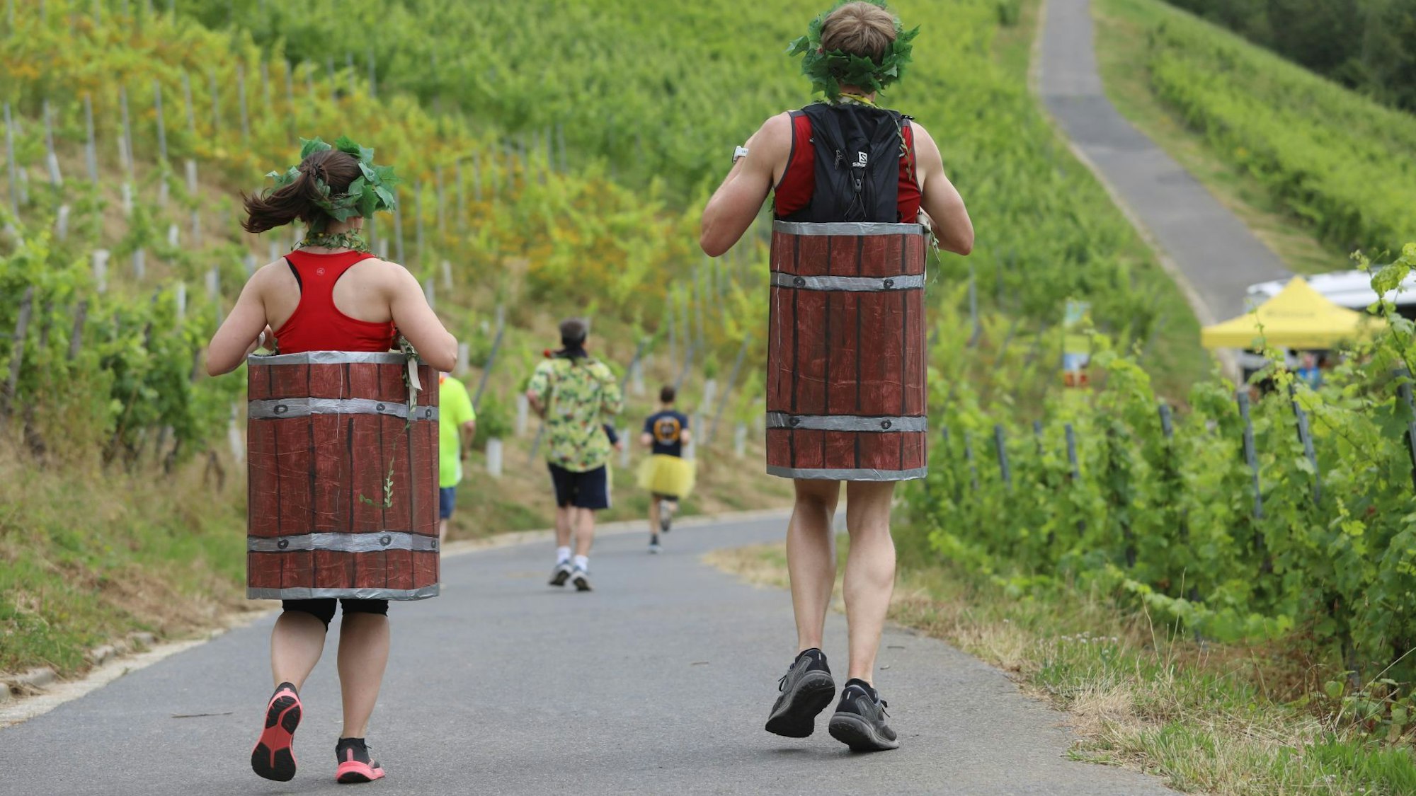 Zwei Läufer, die ein selbst gebasteltes Weinfass am Körper tragen.