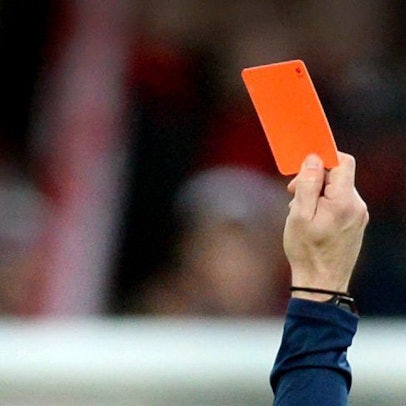 Auf dem Foto ist die Hand eines Schiedsrichters zu sehen, der eine rote Karte zeigt.