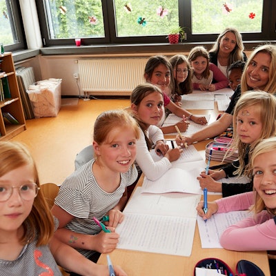Schüler der Klasse 3a der Grundschule Reifferscheid sitzen mit ihrer Lehrerin und einer Teilnehmerin der Aktion Tagwerk an einem Tisch.