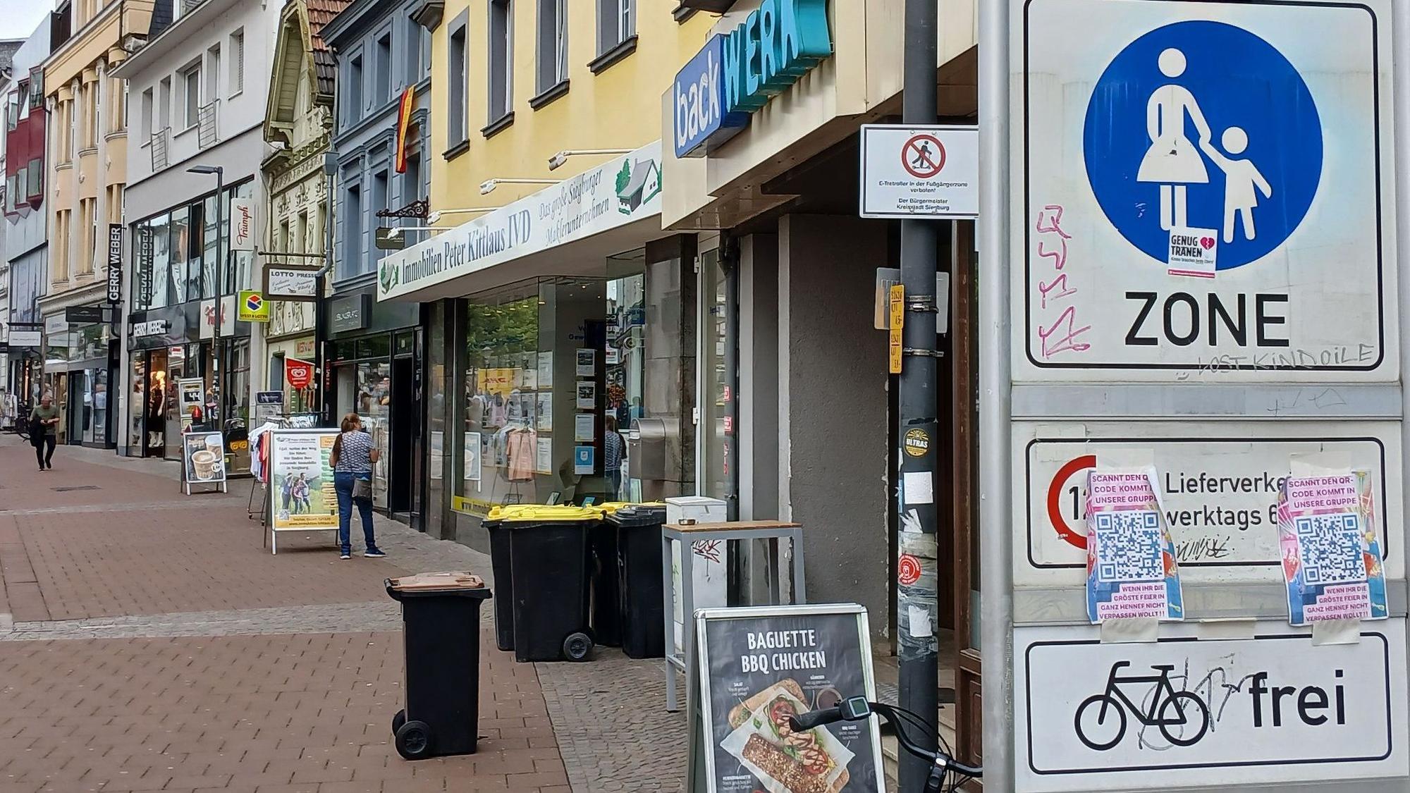 Eine Fußgängerzone, im Vordergrund ein Verkehrsschild, das ein Verbotsschild für E-Scooter verdeckt