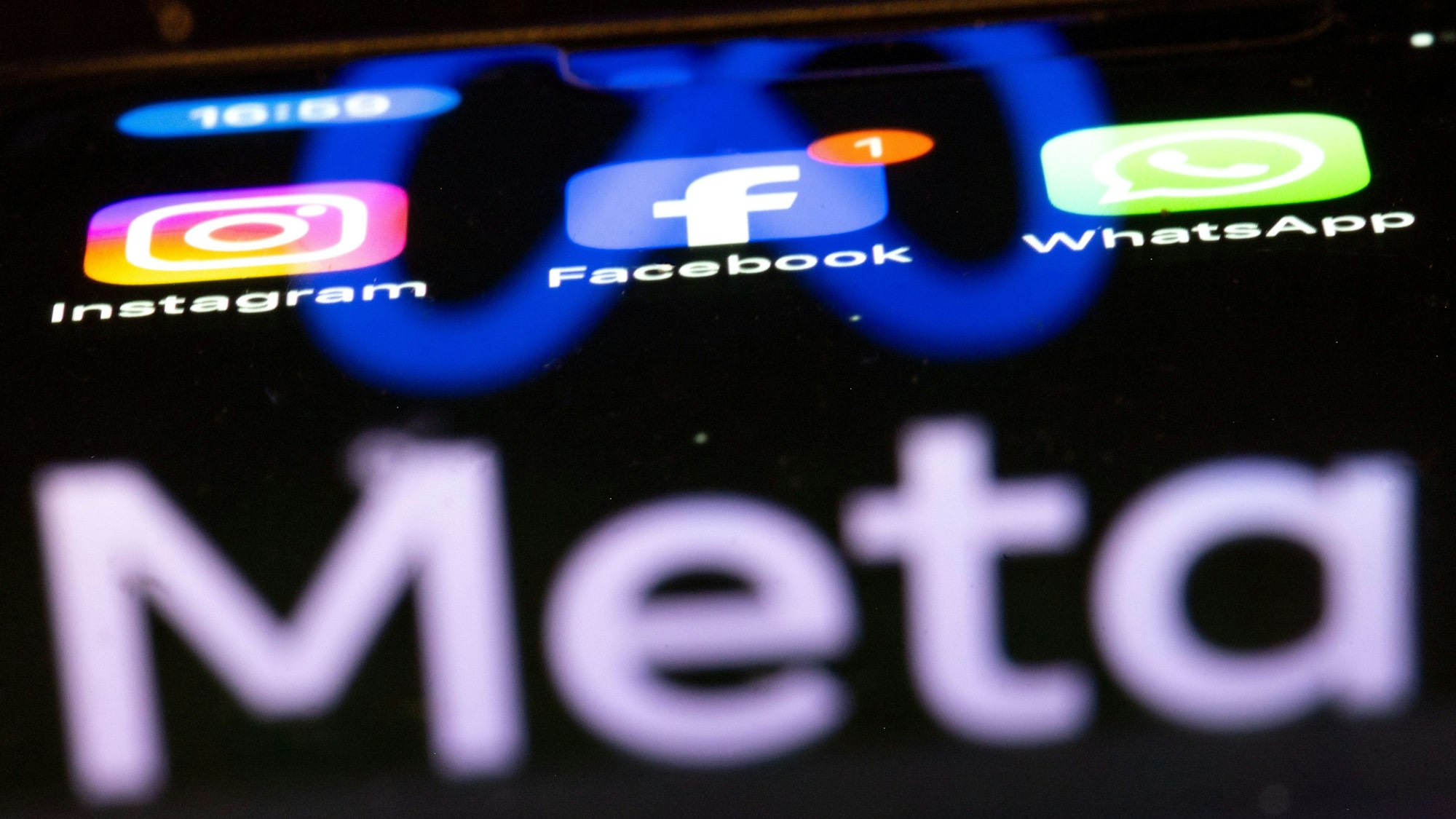 Die Apps Instagram, Facebook und WhatsApp sind auf dem Display eines Smartphones zu sehen, indem sich das Logo des Internetkonzerns Meta spiegelt. (Symbolbild)