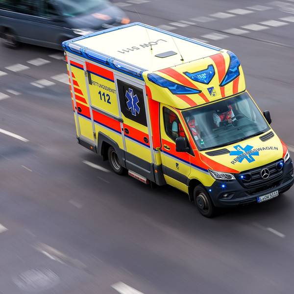 Ein Rettungswagen fährt mit Blaulicht über eine Straße.